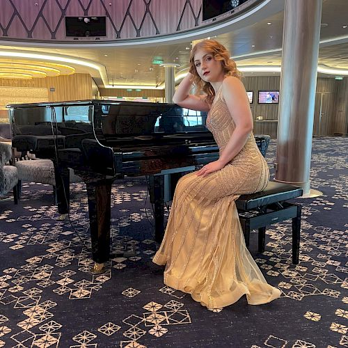 A woman in an elegant gown sits on a piano bench in a stylish, modern room with intricate carpet and luxurious surroundings.
