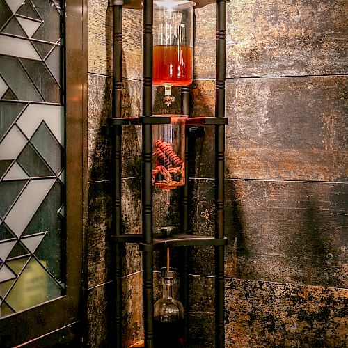 The image shows a corner shelf with three levels, holding a red liquid in a glass container, a decorative hand, and a beaker with a dark substance.